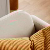Nahaufnahme eines modernen Sofas. Beige Kissen, Cord in warmem Ton, klare Linien.