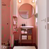 LINDBYN Spiegel in rosa Badewanne, schwarzer Rahmen, über weißem Waschbecken, reflektiert einen weiteren Spiegel.