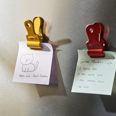 Zwei Notizen zum Kühlschrank: eine gezeichnete Katze, Geburtstagserinnerung des Vaters; Andere Listen Zutaten für Caramel Macchiato Kaffee. Gehalten von magnetischen Clips.