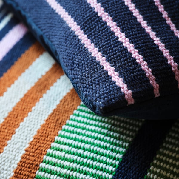 Eine Nahaufnahme aus aufwendig gewebtem, gestreiftem Stoff, der leuchtende Farben und eine hochwertige Textur zeigt.