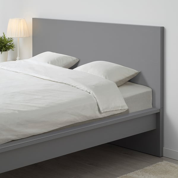 Modernes graues MALM-Bett mit strahlend weißer Bettwäsche, hohem Kopfteil und schlankem Design.