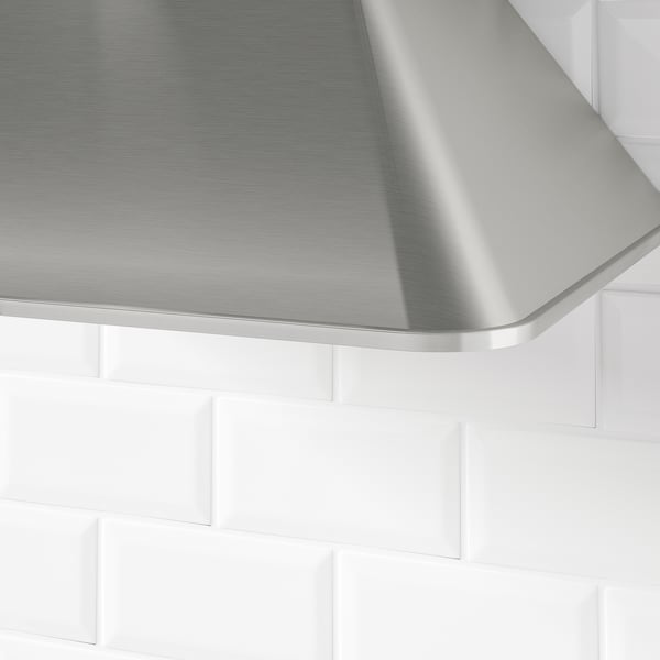 Dunstabzugshaube aus Edelstahl mit elegantem Finish und abgerundeten Kanten, montiert auf weißer Fliesenrückwand.