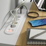 Weißer MITTZON Schreibtisch mit Steckdosen, Smartphone und Notebook.