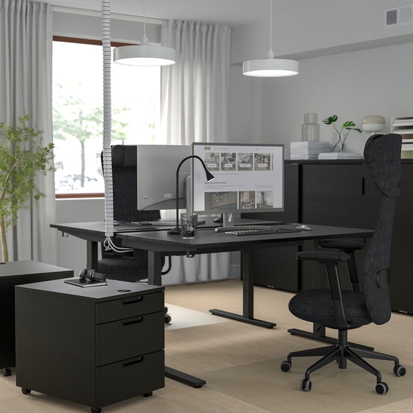 Modernes Homeoffice mit höhenverstellbarem Schreibtisch, Stuhl, Monitor, Lampe und Pflanzen. Großes Fenster und stilvolle Beleuchtung.
