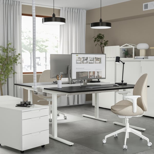 Modernes Homeoffice mit verstellbarem MITTZON-Schreibtisch, ergonomischem Stuhl, Computer-Setup, Pendelleuchte und großem Fenster mit beigem Vorhang.
