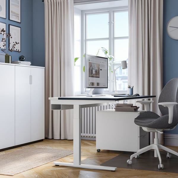 Modernes Homeoffice mit verstellbarem Schreibtisch, Fenster, Stuhl und minimalistischem Dekor.