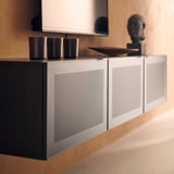 Modernes Sideboard mit metallic-silbernen MÖRTVIKEN-Türen mit perforiertem Design, in dem sich drei dunkle Tassen und eine dekorative Skulptur befinden.