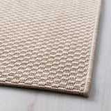 Weicher, beiger gewebter Teppich auf Holzboden, der hochwertige Textur und Design zeigt.