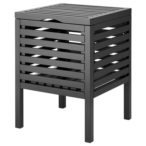 Ein schwarzer MUSKAN-Hocker aus massiver Espe mit lackierter Oberfläche. Sein Design besteht aus horizontalen Lamellen und starken Beinen, die Stauraum unter dem Deckel bieten.