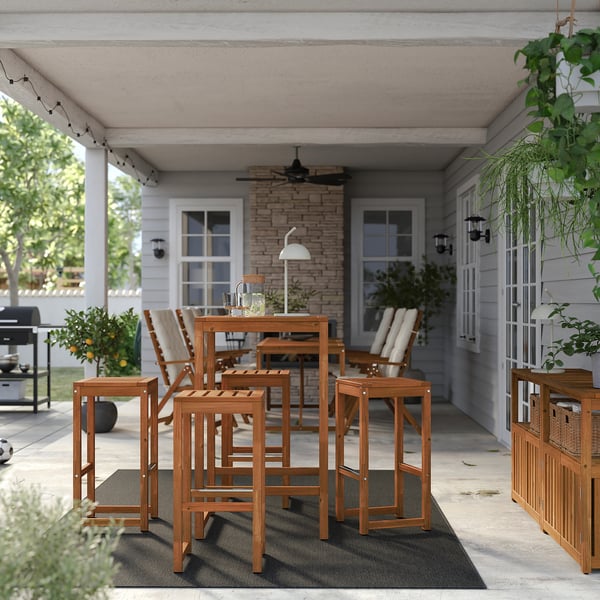 Hölzerne NÄMMARÖ Terrasse auf Teppich, Haus mit Veranda, Pflanzen, Beleuchtung.