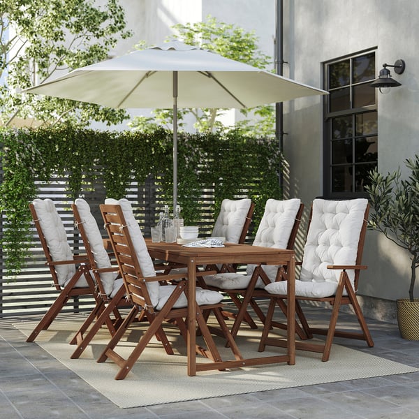 Terrassengarnitur aus Akazienholz mit 6 Klappstühlen, Sonnenschirm und Teppich mitten im Grünen.