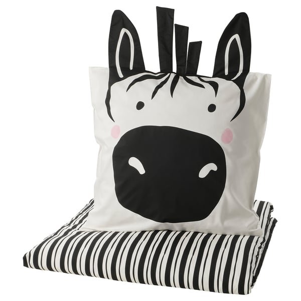 Kissen und Decke mit Zebra-Motiv: schwarz-weiße Streifen, weicher Stoff, verspieltes Design.