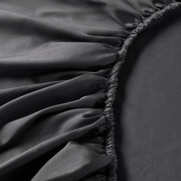 Nahaufnahme eines luxuriösen, glänzenden Bettwäschestoffs mit eleganten, gerafften Details, die seine weiche, satingewebte Textur zur Geltung bringen.