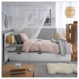 Modernes Schlafzimmer mit NORDLI-Bett, hellrosa Bettwäsche, weißen Schubladen, Baldachin und Hängelampen.