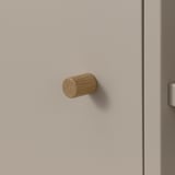Kleiner Holzhaken, der an einer beigen Wand montiert ist und ein schlichtes und minimalistisches Design aufweist, ideal zum Aufhängen von leichten Gegenständen wie Handtüchern oder Schlüsseln.