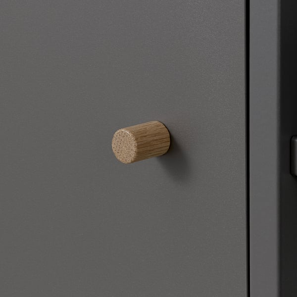 Ein moderner, minimalistischer Schrank mit mattgrauer Oberfläche und zylindrischem Holzgriff, der hochwertiges Design und Handwerkskunst zeigt.