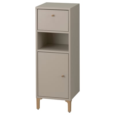 Ein NORSÄLVEN Badezimmerschrank in Beige. Es besteht aus einer Schublade, einer Tür und einem offenen Regal. Der Schrank hat ein schlankes Design mit Holzbeinen.