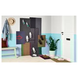 Heller Flur mit weißer Tür, blauer Wand, bunten Matten, Bank mit Hut und Mantel und einer Topfpflanze.