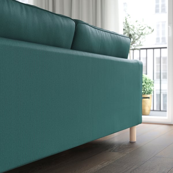 Blaugrünes Sofa in der Nähe des Fensters mit Topfpflanze, abnehmbarem, maschinenwaschbarem Bezug und Holzbeinen.