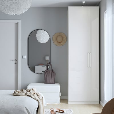 Minimalistisches Schlafzimmer mit weißem PAX-Kleiderschrank, Spiegel und Kommode, Lampe und hellen Farben.