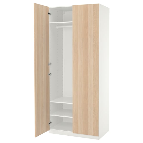 Ein offener ikea PAX Kleiderschrank in Weiß mit hellen Holztüren. Es hat Regale und eine Kleiderstange im Inneren.