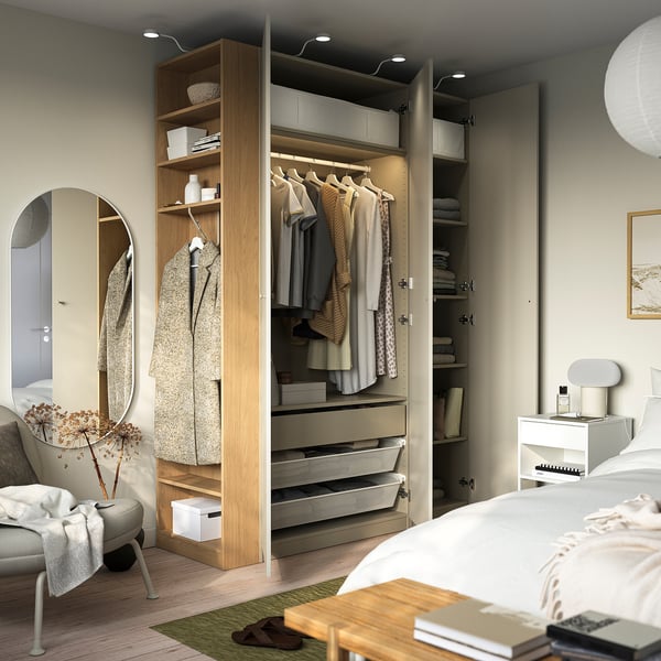 Schlafzimmer mit großem Kleiderschrank, hängender Kleidung, Regalen, Schubladen und eingebauter Beleuchtung.