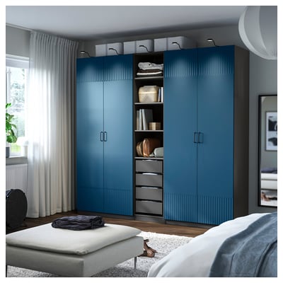 Blauer PAX-Kleiderschrank im modernen Schlafzimmer, hoch neben dem Fenster, mit Schubladen und Regalen.