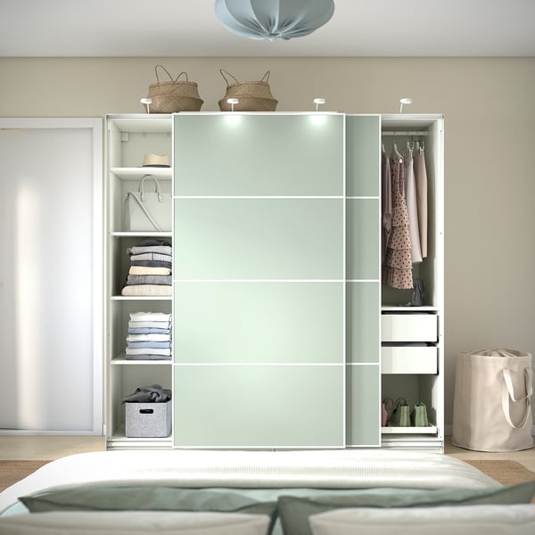 Ein moderner Kleiderschrank mit Schiebetüren, integrierter Beleuchtung und Regalen für Kleidung und zusammengefaltete Gegenstände.