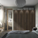 Modernes Schlafzimmer mit großem PAX-Kleiderschrank aus Holz, Spiegel, Deckenleuchten, Blumen und gemütlichem Bett.