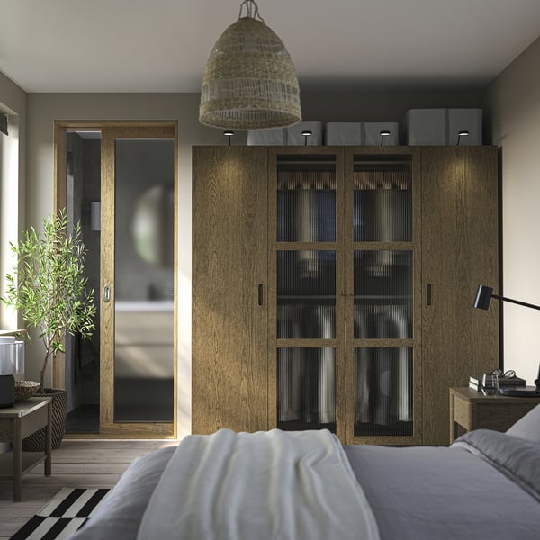 Modernes Schlafzimmer mit PAX-Kleiderschrank, Bett und Korblicht. Minimalistisches Design, Holzböden, Pflanzen.