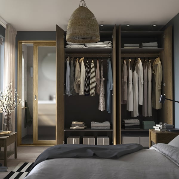 Offener Kleiderschrank mit Kleidung und Kisten; graues Bett, Pendelleuchte