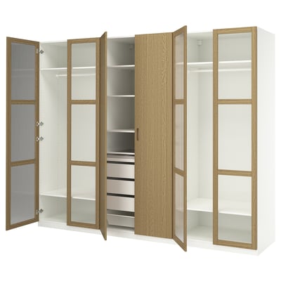Dieses Bild zeigt einen weißen PAX-Kleiderschrank mit Eichenfurniertüren, Glasböden und Metallschubladen. Es verfügt über Kleiderstangen und verstellbare Fächer.