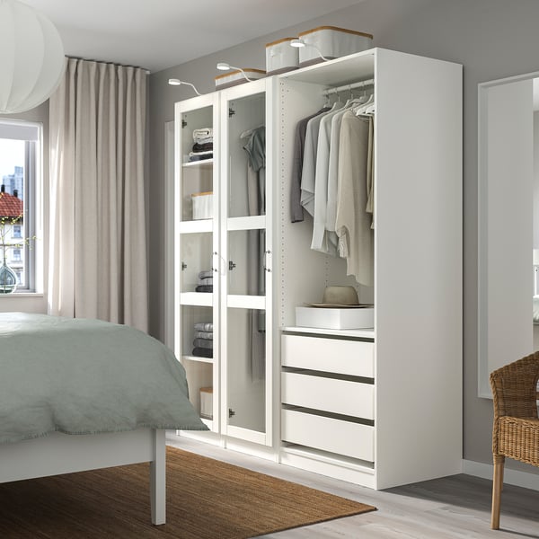 Moderner, weißer PAX-Kleiderschrank im Schlafzimmer mit Spiegel, Kleidung und Schubladen.