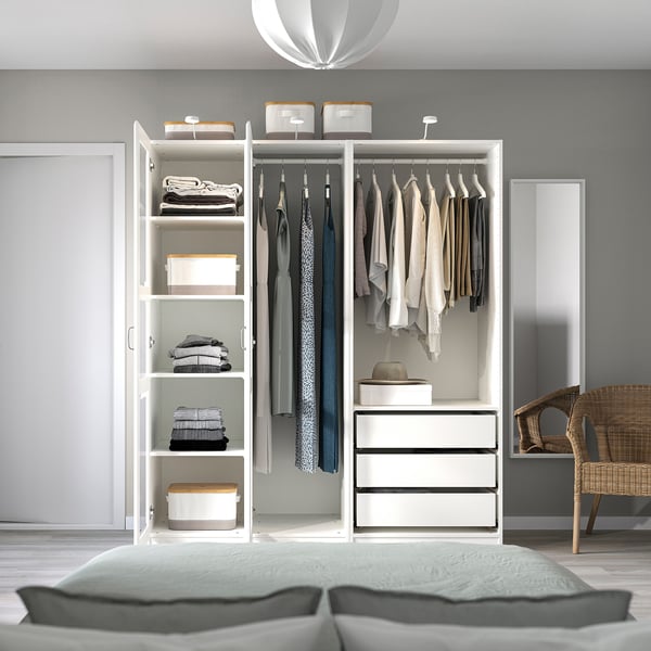 Minimalistisches Schlafzimmer mit offenem PAX-Kleiderschrank, ordentlich organisierter Kleidung und gemütlichem Bett mit grauen Kissen.