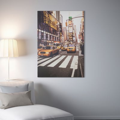 Große Wandkunst, die New Yorks belebte Straße mit gelben Taxis zeigt, hängt über einem Bett in einem aufgeräumten Zimmer.