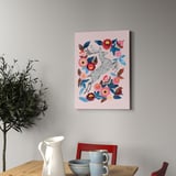 Kunstdruck mit Hirschen und Blumen, gerahmt an der Wand, neben Holztisch mit Pflanze, Tassen und Schale.