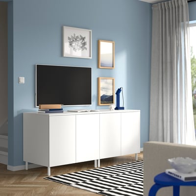 Modernes Wohnzimmer mit blauen Wänden, PLATSA-Stauraum, TV, gestreiftem Teppich, grauen Vorhängen und Kunstrahmen.