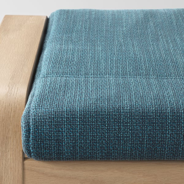 Ein blauer gepolsterter Fußhocker auf einem Holzsockel, der für Komfort und Entspannung konzipiert ist.
