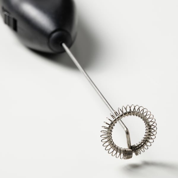 Schwarzer Milchaufschäumer mit Metallspirale auf weißem Hintergrund, kompakt für eine einfache Kaffeezubereitung.