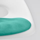 Nahaufnahme eines weichen, grünen Kissens auf einem weißen Stuhl, das Komfort und umweltfreundliche Materialien zeigt.