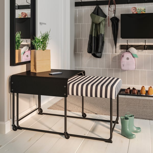 Moderne gestreifte RÄVSAL-Bank mit Ablagetisch und Rädern. Zwei Sitzplätze, in der Halle mit Garderobe, Stiefeln und Pflanze.