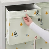 Das Bild zeigt eine Hand, die eine Stoffkiste mit Waldillustrationen aus einem weißen Regal zieht. Die Box sitzt perfekt und hat Griffe zum einfachen Entfernen.