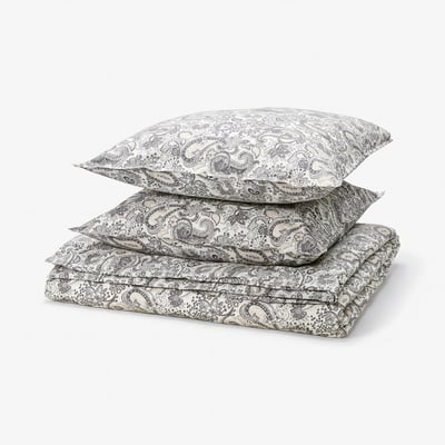 Stapel beige Paisley-Bettwäsche: Bettdecke und zwei Kissen, 80 % Baumwolle, 20 % Viskose, kunstvolles Blumenmuster.