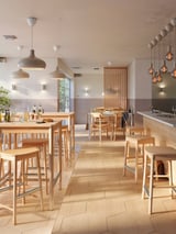 Modernes Café mit Holztischen und -stühlen, warmer Beleuchtung und minimalistischem Design.