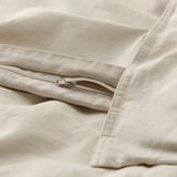 Nahaufnahme eines beigen Bettbezugs mit Reißverschluss, der die strukturierte Leinen-Baumwoll-Mischung und den funktionalen Verschluss zur Geltung bringt.