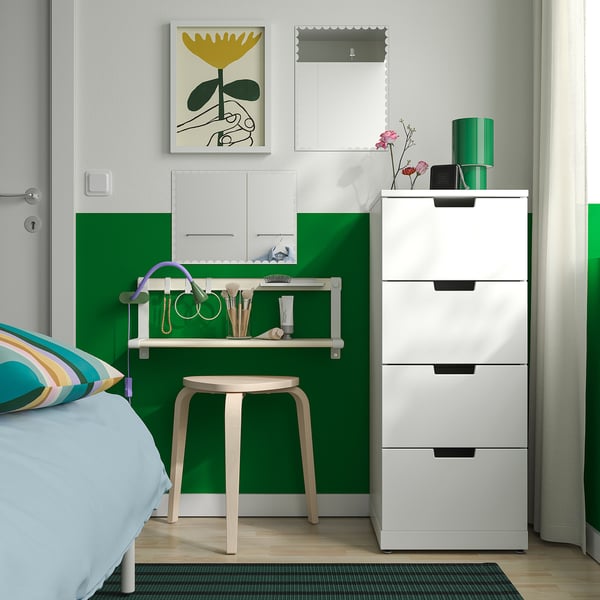 Weiß-grünes Schlafzimmer mit RUNDOXEL-Spiegel, Waschtisch, mehrfarbigem Kissen, grünem Teppich und hoher Schublade.