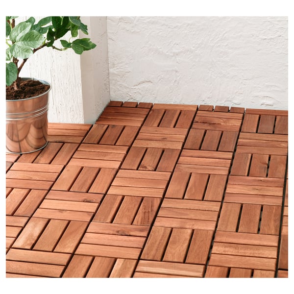 Terrassenfliesen aus Holz auf dem Balkon, ineinandergreifendes Muster. Pflanze in der Nähe.