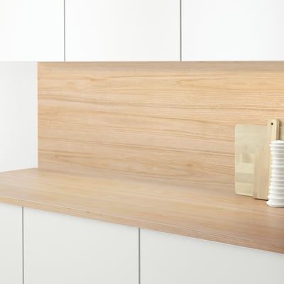 Küchentheke aus Holz mit heller Holzplattenrückwand, in der sich ein Schneidebrett und eine kleine Vase befinden.