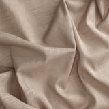 Nahaufnahme von beigen Vorhängen; glatter, strukturierter Stoff, wahrscheinlich Baumwolle. Zerknittert, mit Qualität und Textur.
