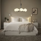 Modernes Schlafzimmer mit Kronleuchter aus Chrom und Glas, weißer Bettwäsche, grauem Überwurf, Nachttischen, Wandleuchten.